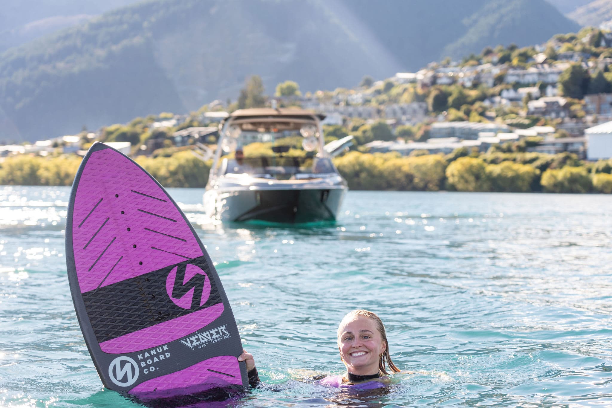 Coach Emma Galusha smiling in the water with her board after a session