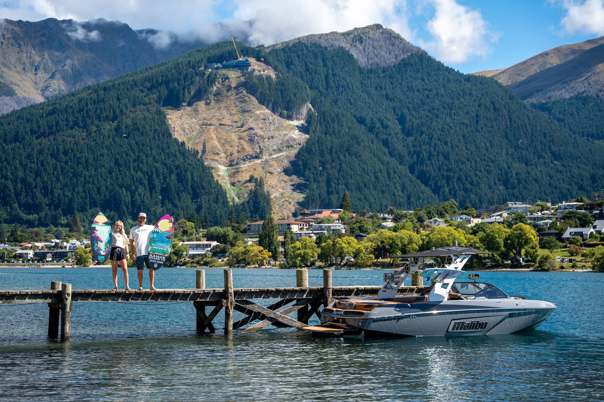 Coaches on the jetty with boards beside the wake boat, Queenstown mountains behind